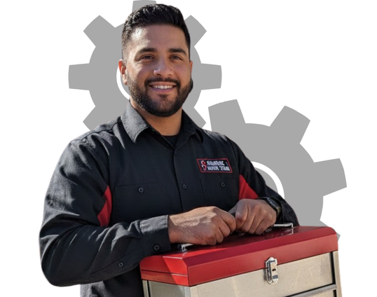 A smiling garage door technician in a black uniform standing in front of an open garage, holding a red professional toolbox.